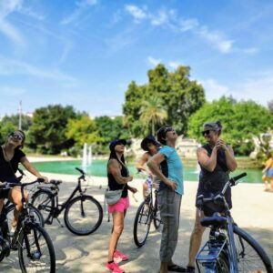 Cyclists on the Be Like Us bike tour by a park fountain in Barcelona